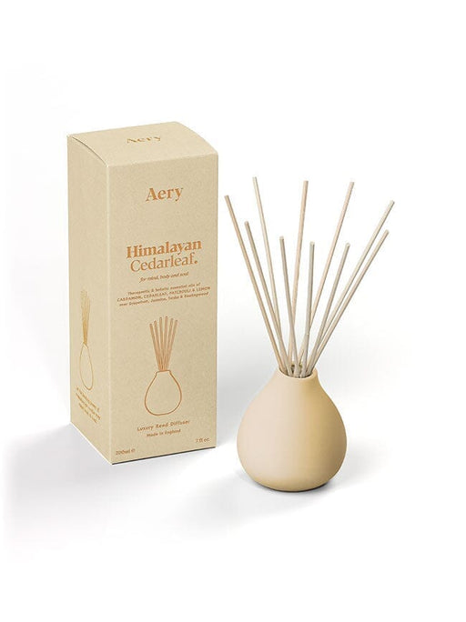 Cream Himalayan Cedarleaf diffuser by Aery displayed next to product packaging on white bacground 