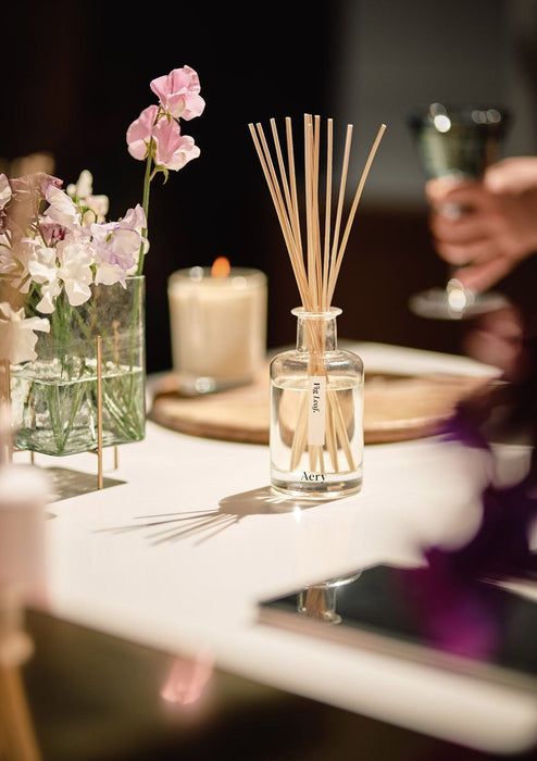 Fig Leaf diffuser by aery displayed next to vase of white flowers on kitchen workspace